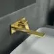 Wand-Waschtischarmatur in Brushed Gold von Ideal Standard, mit eckiger Rosette und einem geraden Auslauf, montiert an einer hellen Oberfläche.